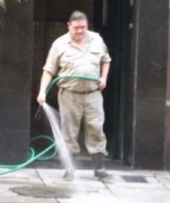 Portero manguereando la vereda